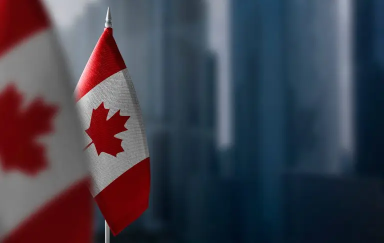 Small flags of Canada on a blurry background of the city